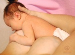 Správna poloha a prisatie pri dojčení, pohľad na bábätko zhora z pohľadu matky. Brada je zatlačená do prsník a medzi nosom a prsníkom je medzera